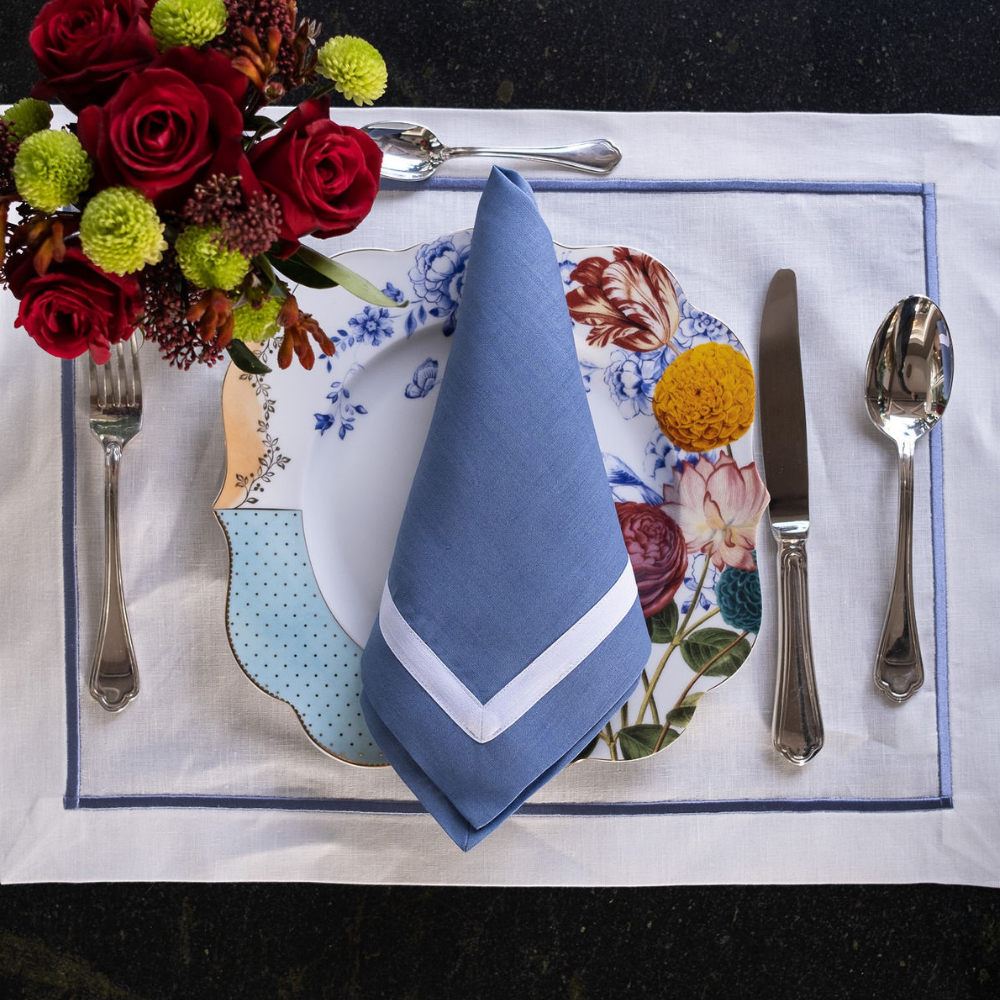 Blue linen napkins with white borders, one folded centerpiece on a table