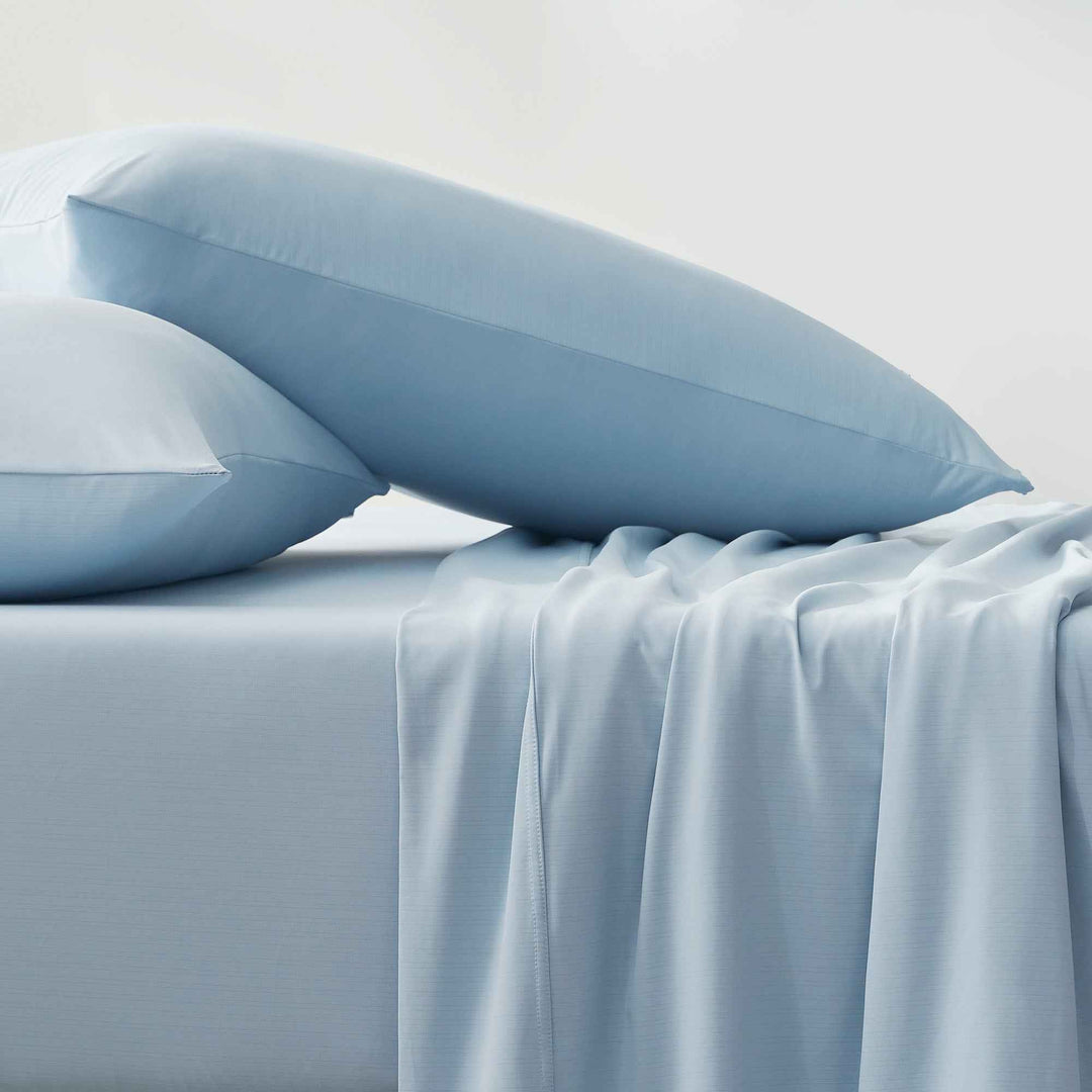 Light blue sheet set with draped fabric and stacked pillowcases