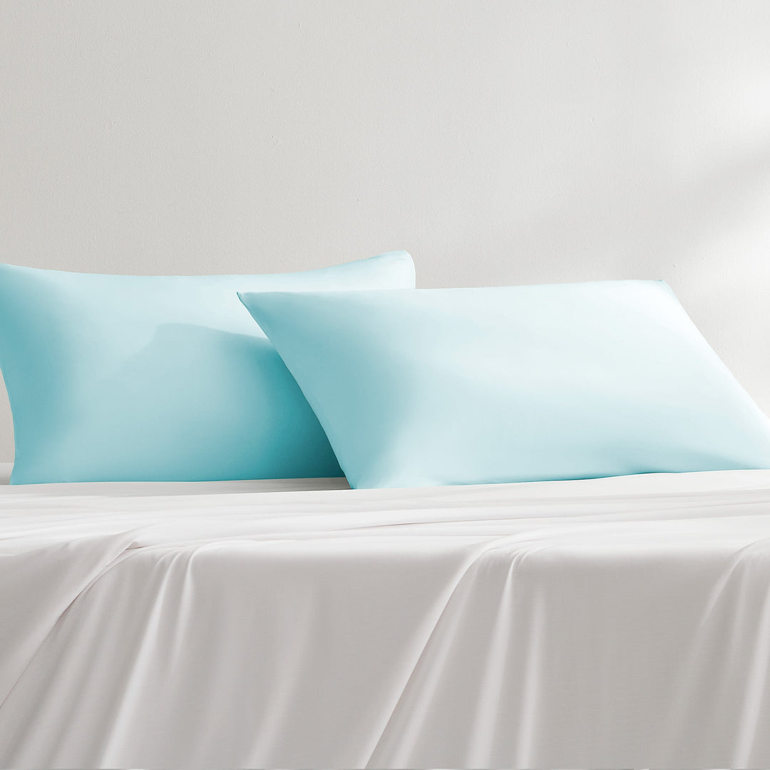 Light blue cooling pillowcase on bed with folded overlap edge, smooth fabric