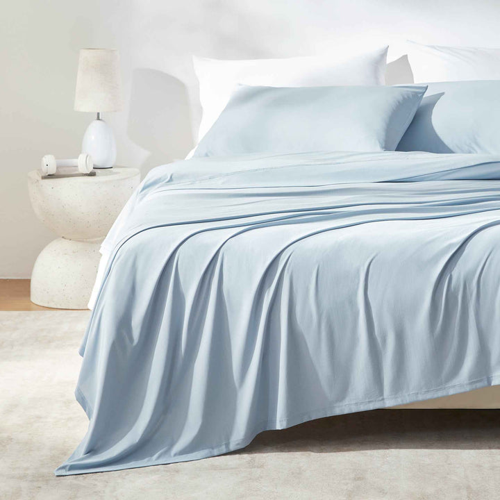 Light blue cooling sheet set on a bed with fitted sheet and flat top sheet