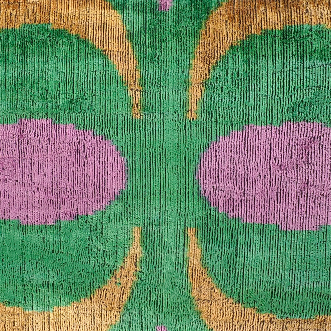 Silk velvet ikat pillow close-up of green and gold arches with purple accents