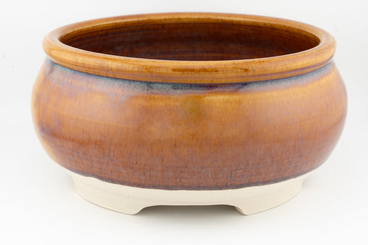 Ceramic bonsai pot in warm brown glaze with darker rim and three feet.