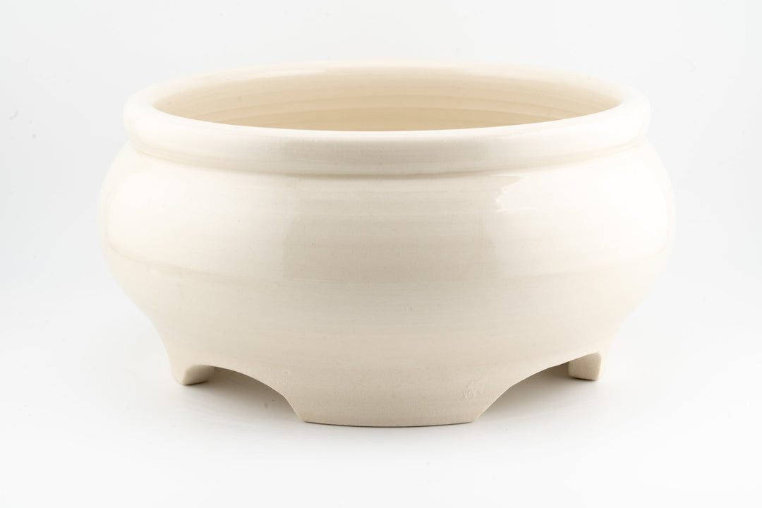 Ceramic bonsai pot in off-white glaze with smooth sides and three feet.