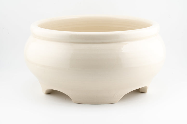 Ceramic bonsai pot in off-white glaze with smooth sides and three feet.