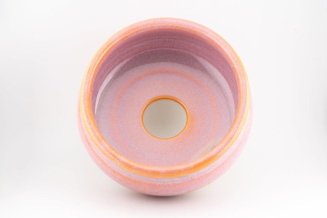 Ceramic bonsai pot top view with pink interior glaze and orange glazed rim.