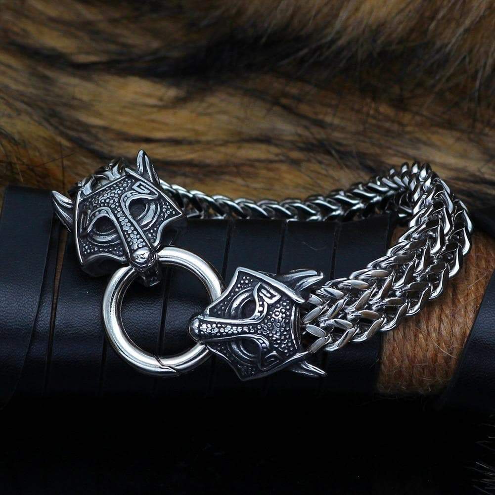 Close-up wolf-head charms on silver chain bracelet with round clasp ring