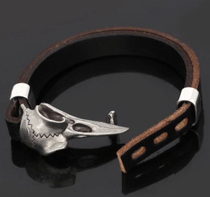 Black leather bracelet with silver-tone raven skull pendant and two-tone studded strap