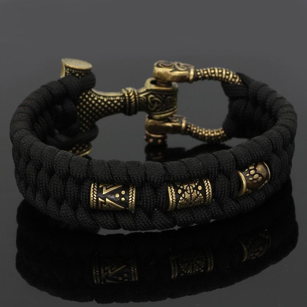 Black paracord bracelet with gold-toned engraved metal centerpiece and braided texture
