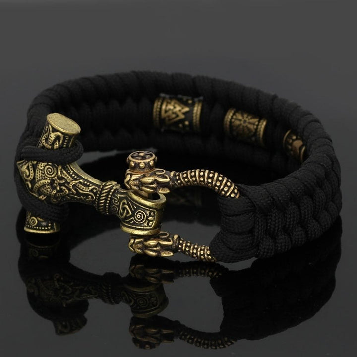 Black paracord bracelet with gold-toned warrior hammer centerpiece