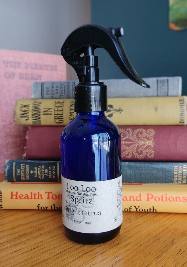 Deodorizing bathroom spray bottle in blue glass with black trigger, Bright Citrus label.