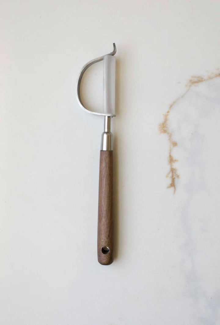 Vegetable peeler with curved stainless blade and brown wooden handle, hanging loop