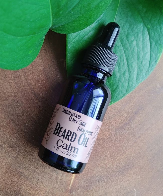Beard oil bottle with black dropper cap and label reading &