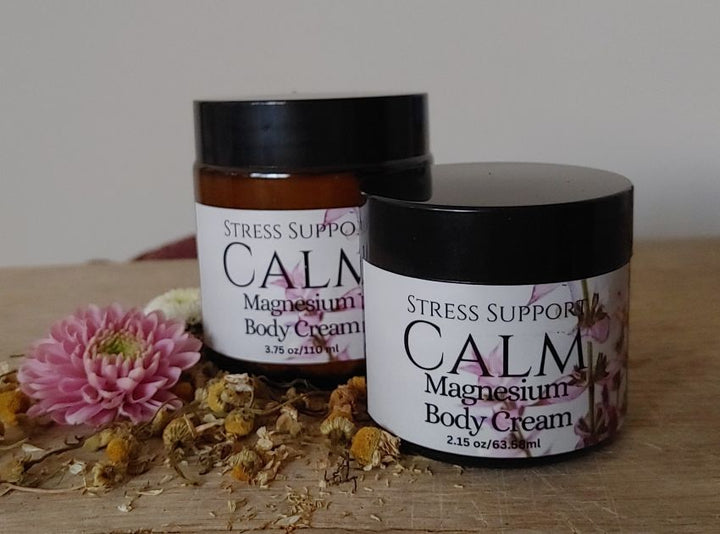 Magnesium body cream jars with black lids, showing labels and pink flower detail