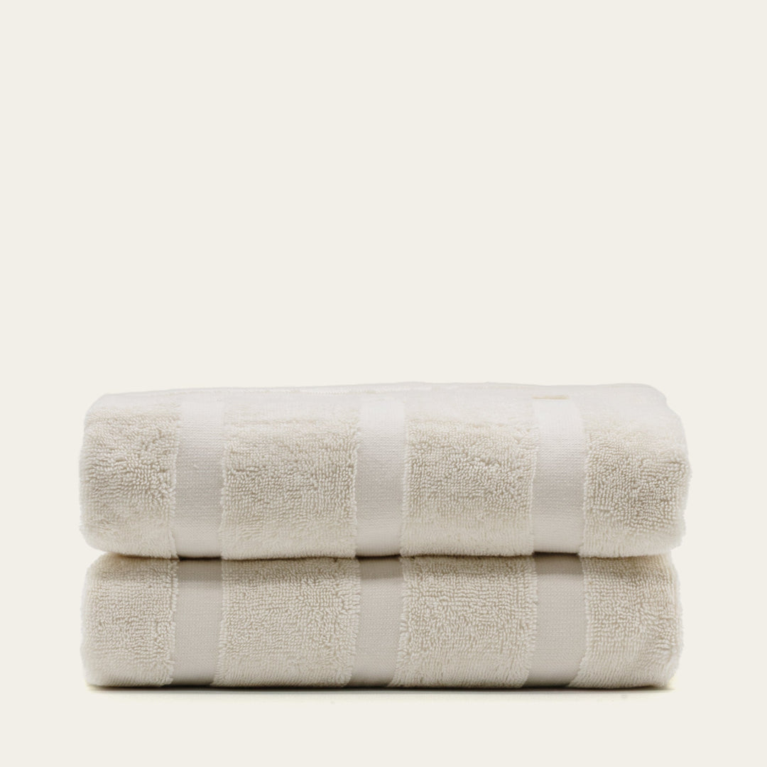 Folded light beige cotton towels with vertical stitched texture bands