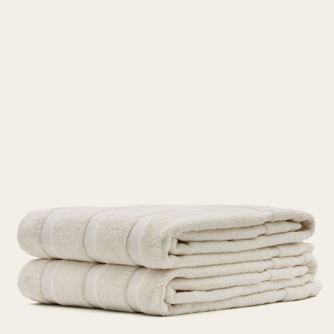 Ecru cotton wash towels stacked, showing terry texture and fold lines
