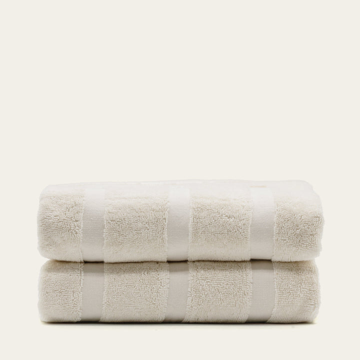 Two ecru cotton towels folded with wide stripe bands