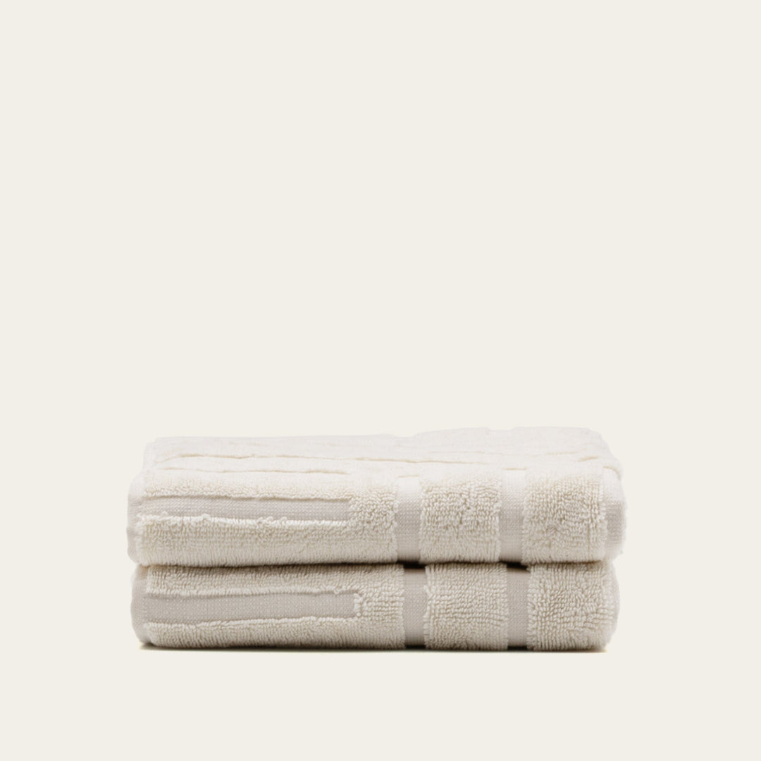 Ecru cotton bath towel, neatly folded with stitched border