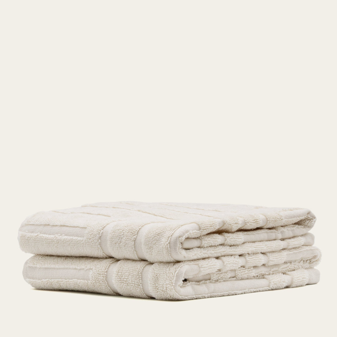 Cotton bath towel set, folded stack of white towels with textured waffle stripe trim