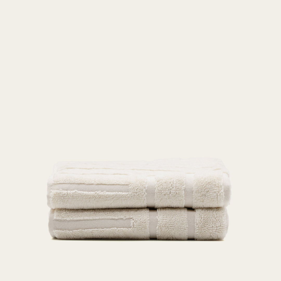 Ecru cotton towels stack, two folded bath towels with woven stripe and textured trim