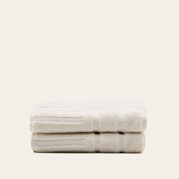 White cotton towel folded into a neat stack with subtle patterned bands