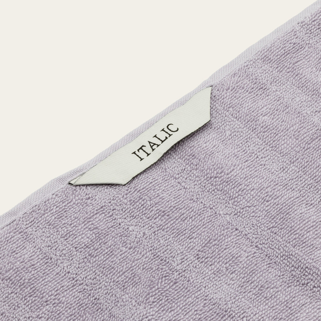 Lilac towel corner with fabric tag reading “ITALIC” and textured loop weave