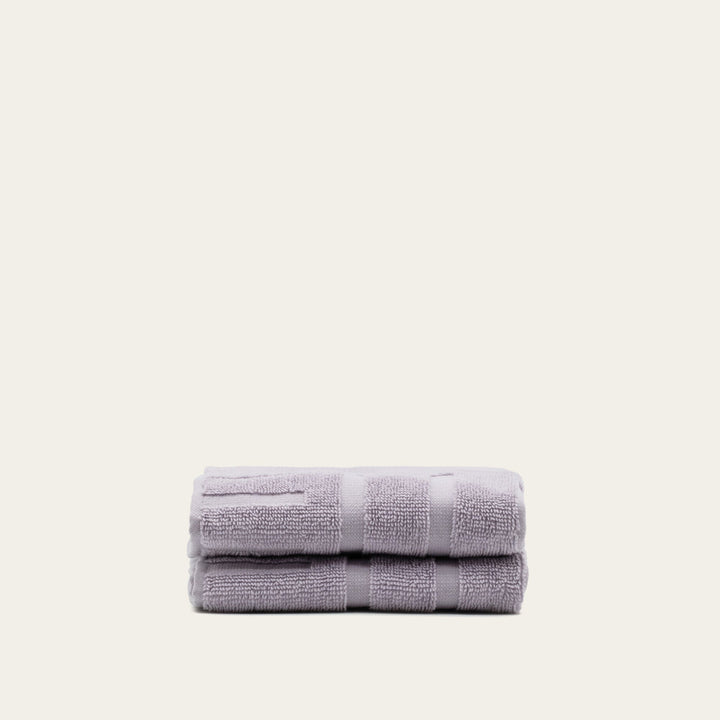Lavender cotton towels neatly folded into a compact stack with striped borders