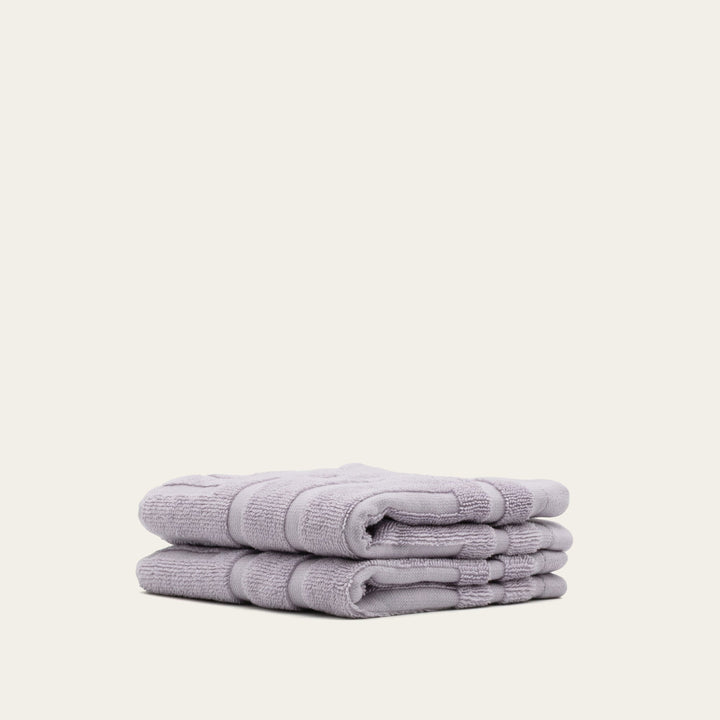Lilac terry towels folded in a stack, shown from the side with layered edges.