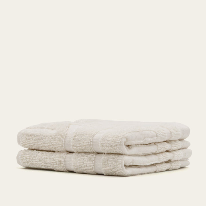 Folded cotton towels in light beige with ribbed border and soft terry texture
