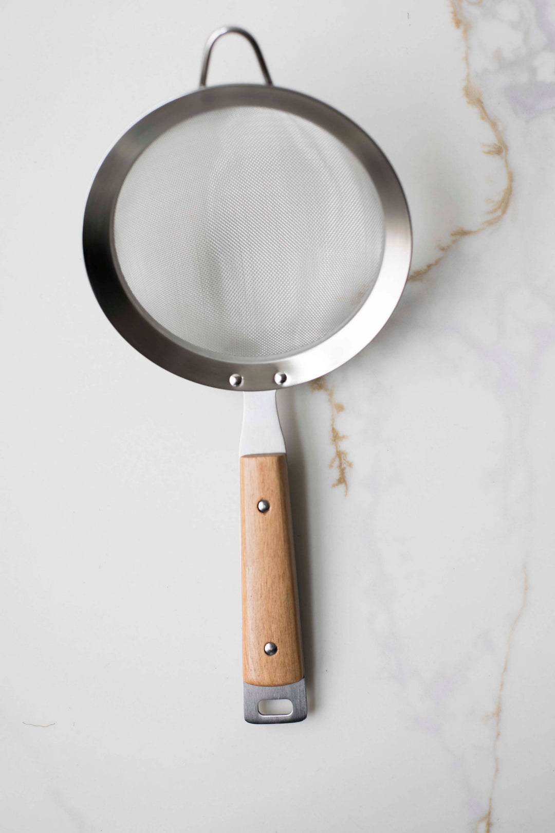 Round mesh strainer with dark metal rim, wood handle with hanging loop