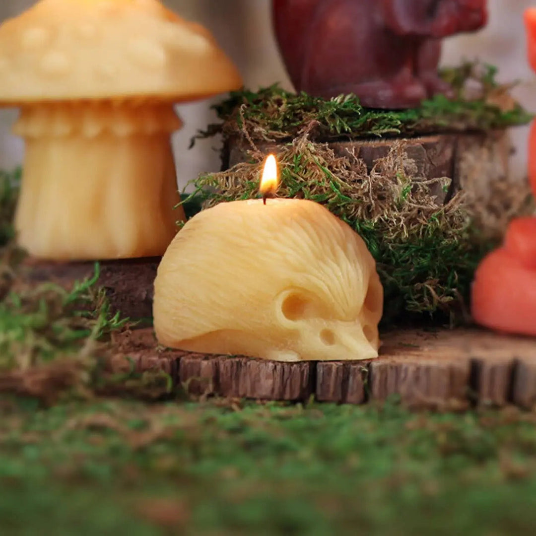 Hedgehog beeswax candle with lit wick on mossy stump