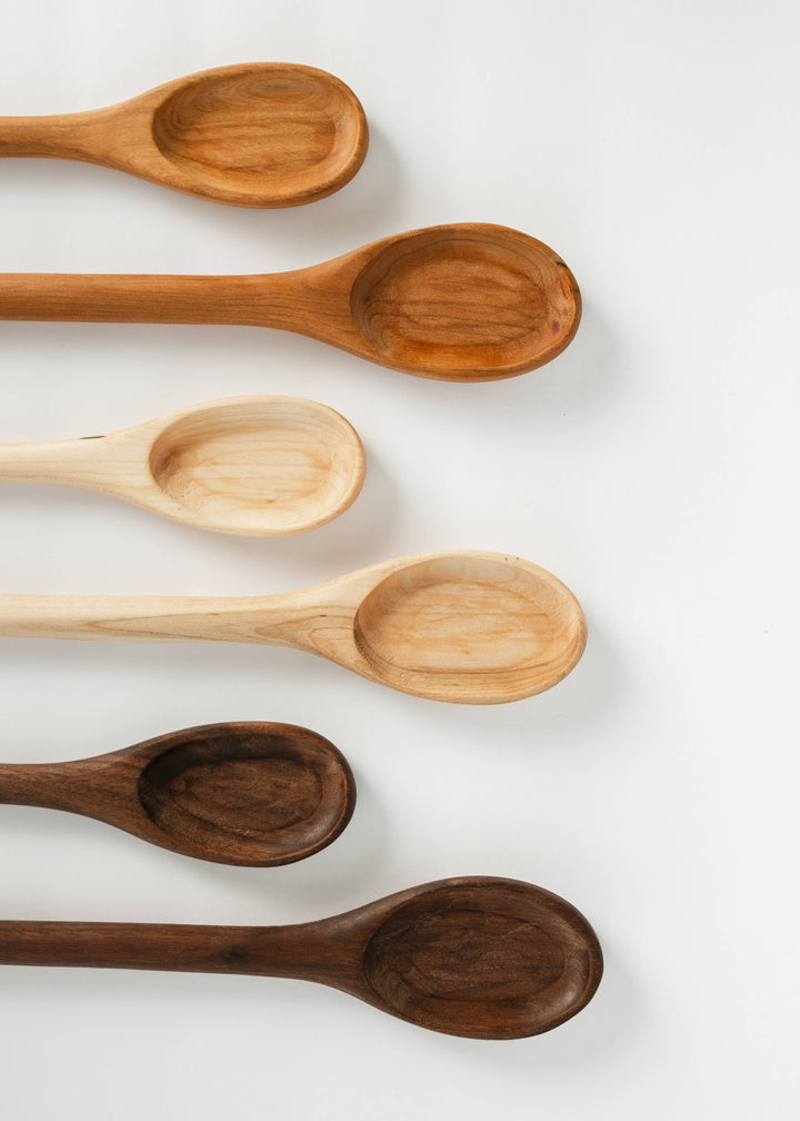 Wooden serving spoon, oval bowl and long handle in warm light-brown grain