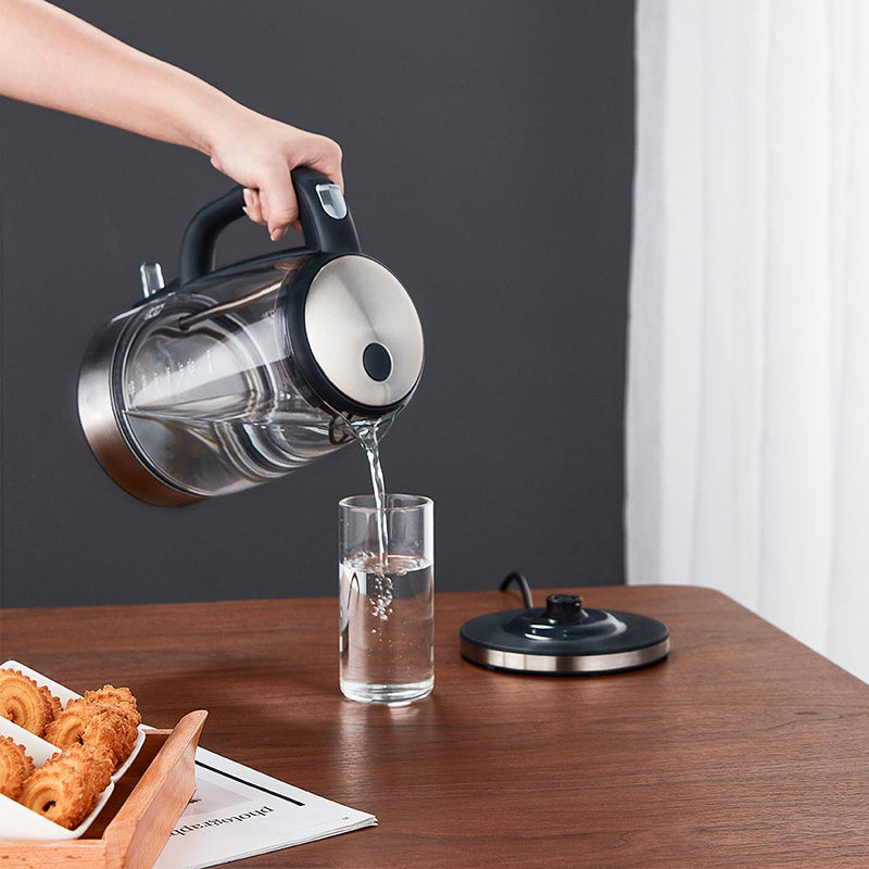 Stainless and black electric glass kettle pouring water from a spout into a cup