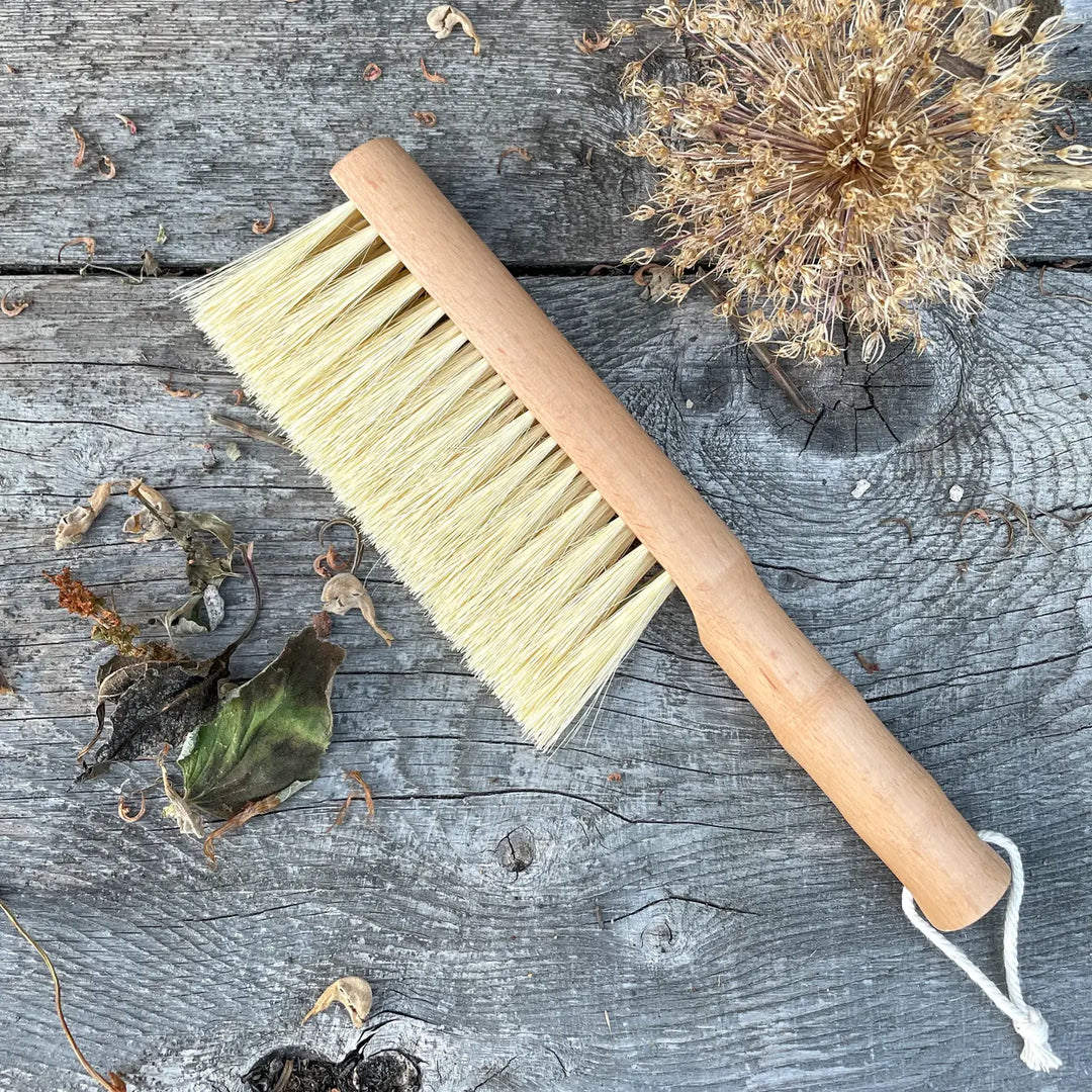Garden brush with wooden handle and pale yellow bristles, twine tie end