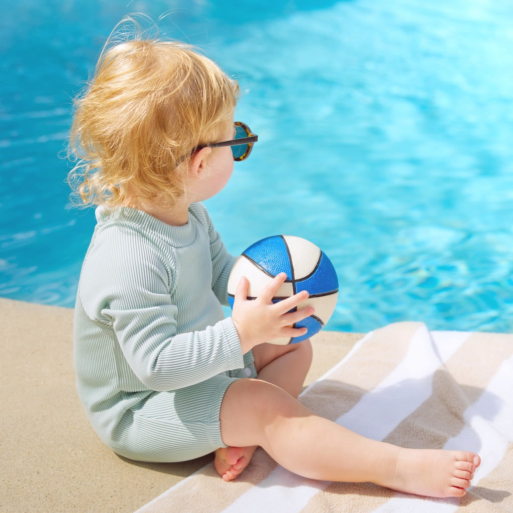 Mint ribbed long-sleeve rash guard swimsuit with shorts, holding beach ball
