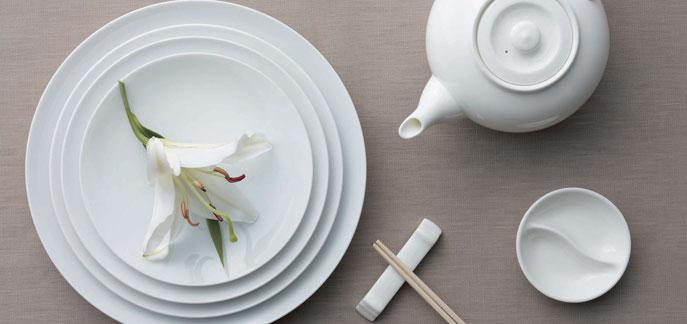 Set of white round saucers with concentric rings, stacked with one loose saucer