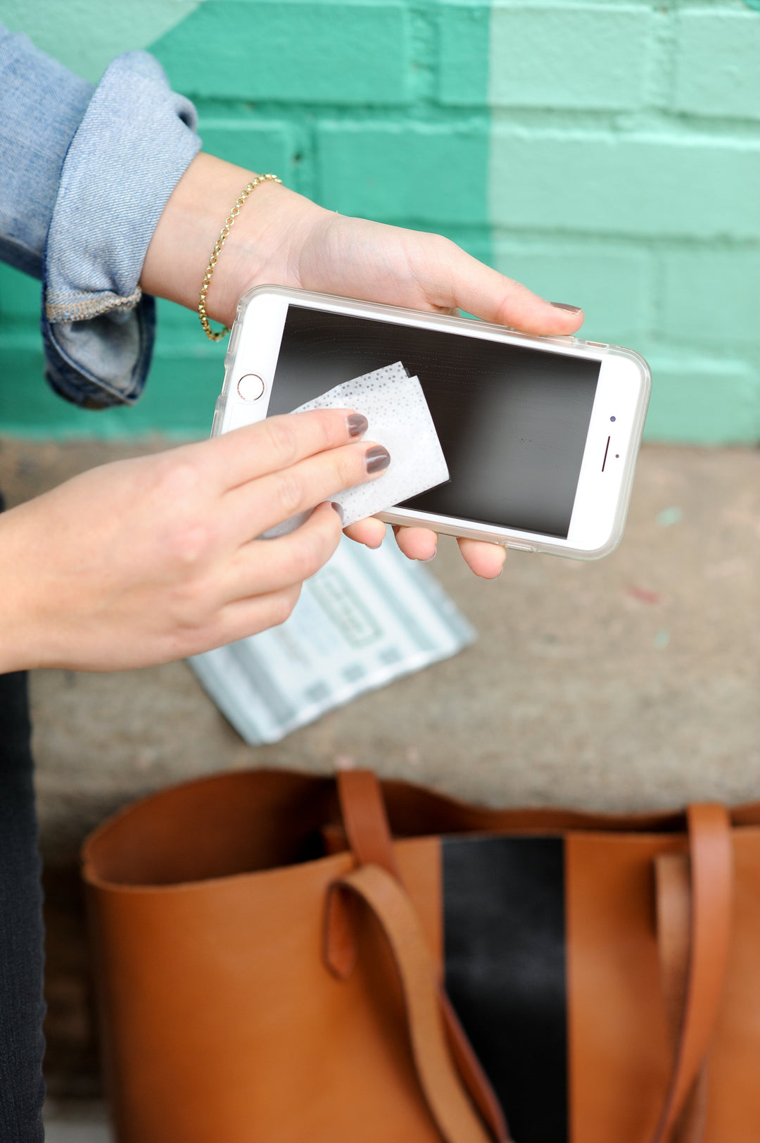 Hand wiping a smartphone screen with a screen-cleaning wipe