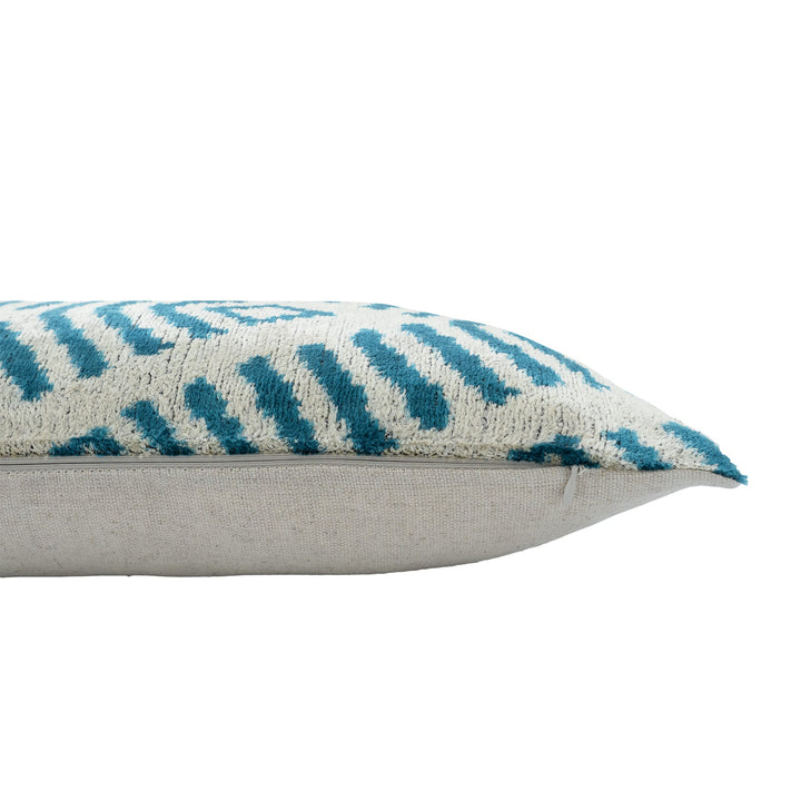 Cream ikat pillow cover with blue pattern, shown from the side