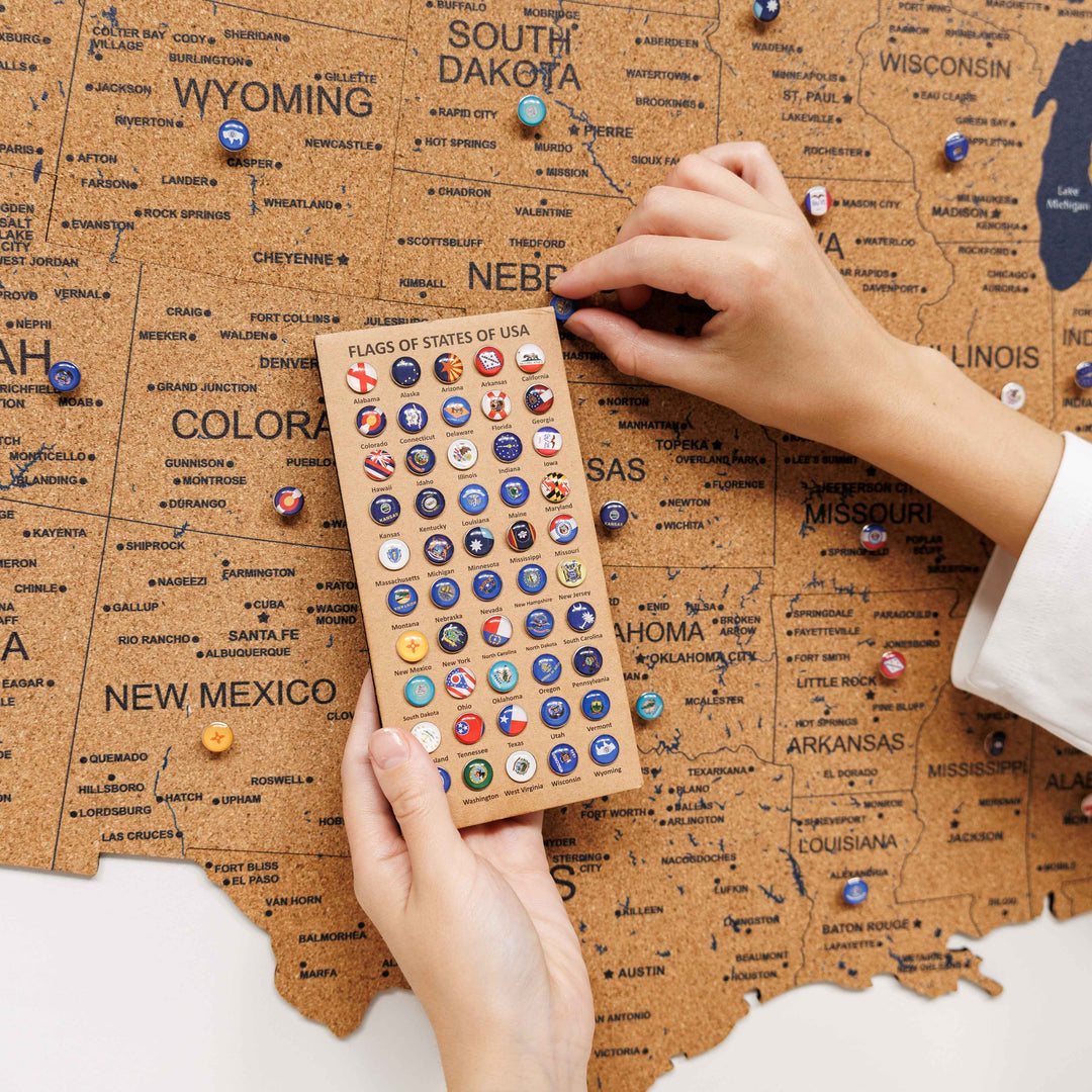 Cork USA map close-up with flag-style sticker pins and a hand placing one