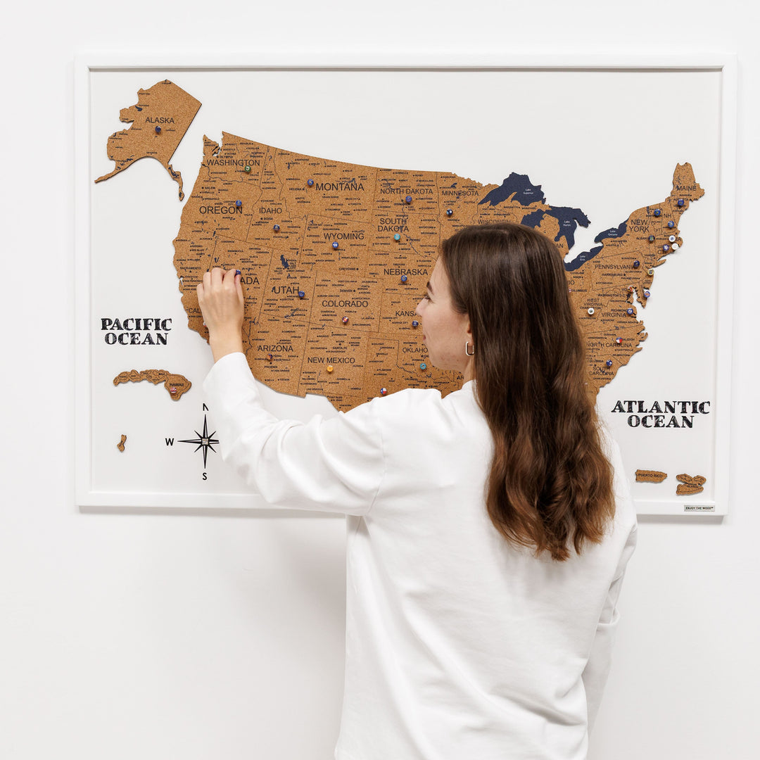 Woman pressing push pins on a framed cork USA map