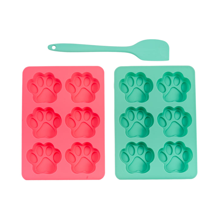 Two silicone square baking trays with paw-shaped molds and a turquoise spatula