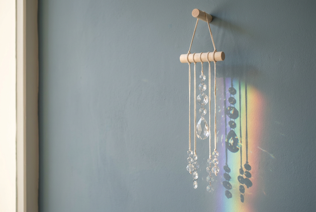 Crystal suncatcher with a soft faded-denim blue background and sunlight casting a rainbow