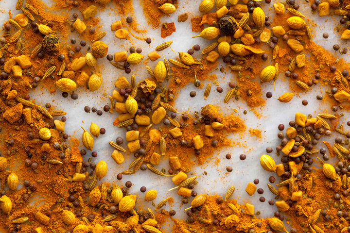 Whole curry spice mix with seeds and flakes scattered on a surface