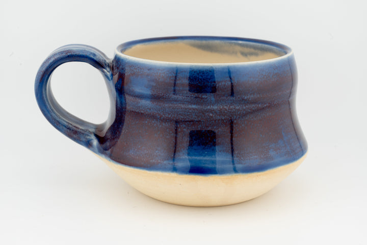 Ceramic wide mug with deep blue glaze, side view with loop handle and rounded body