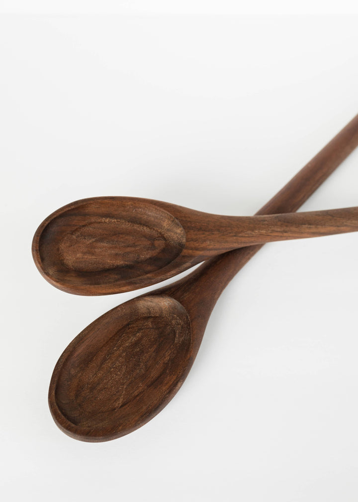 Two dark wooden spoons with oval bowls and long handles, curved bowl ends