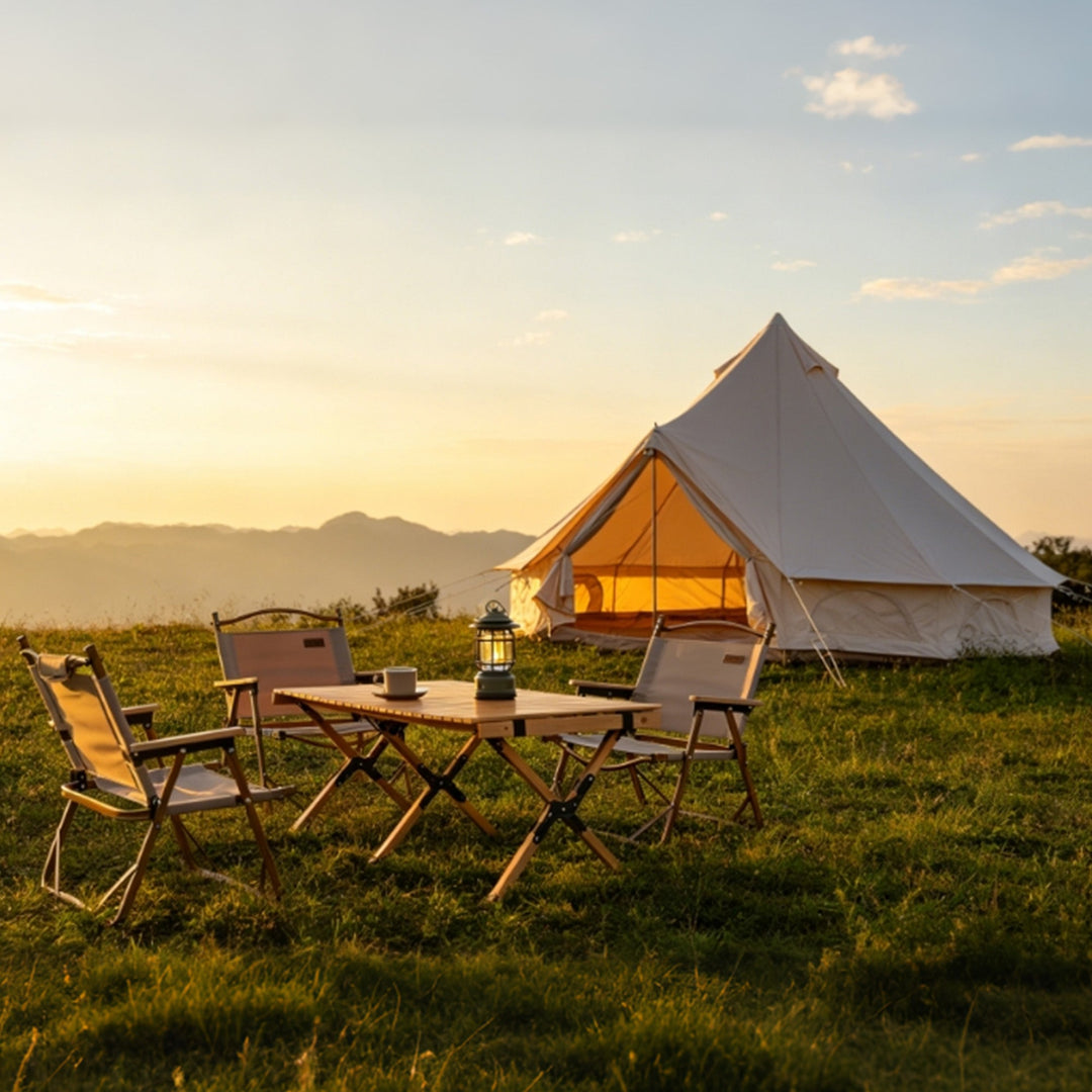 Beige bell tent on a grassy campsite with outdoor folding table and chairs