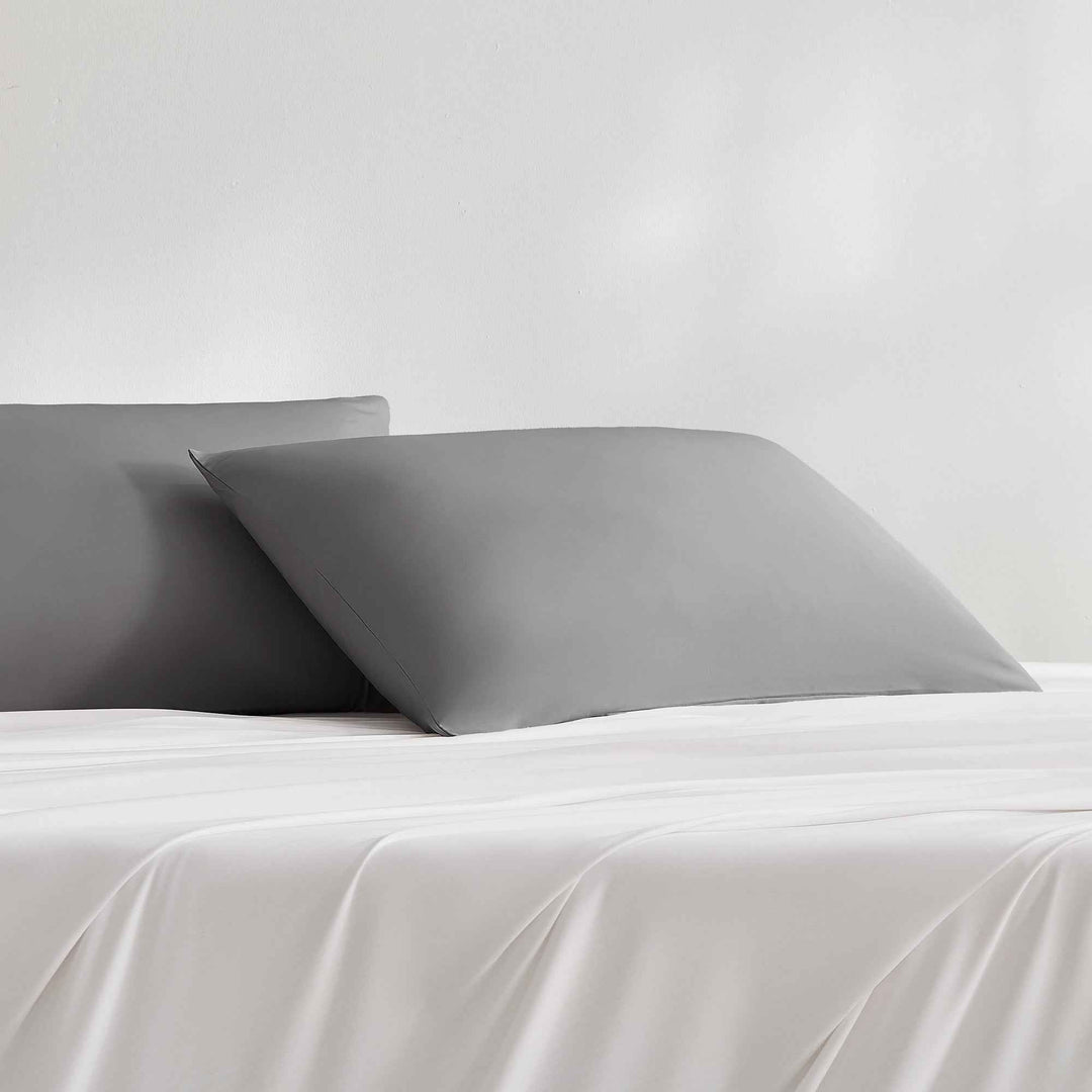 Gray cooling pillowcase on bed, smooth fabric with stitched edges