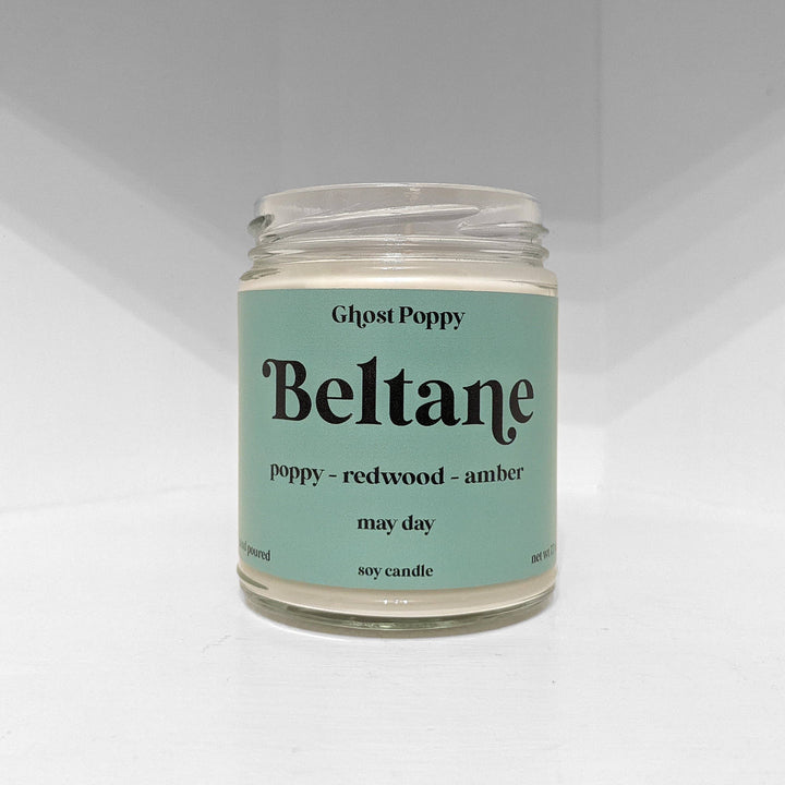 Soy candle in clear glass jar with teal label, Ghost Poppy may day scent