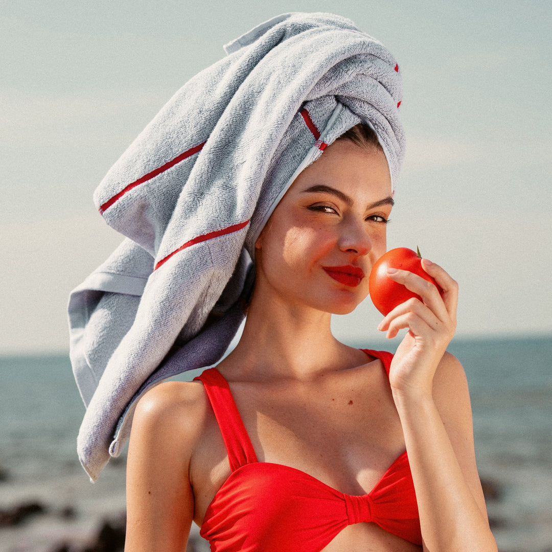 Turquoise-blue cotton towel with red stripe, draped over head and shoulders