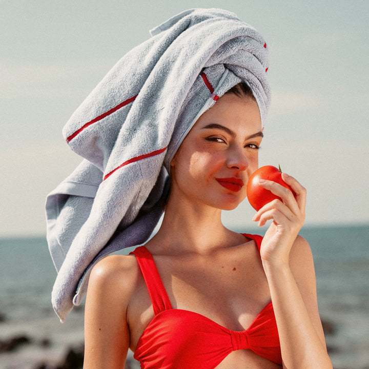 Turquoise-blue cotton towel with red stripe, draped over head and shoulders