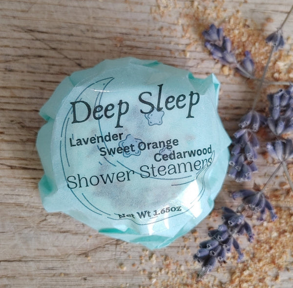 Teal wrapped round shower steamer with printed label, lavender sprigs, and dried bits